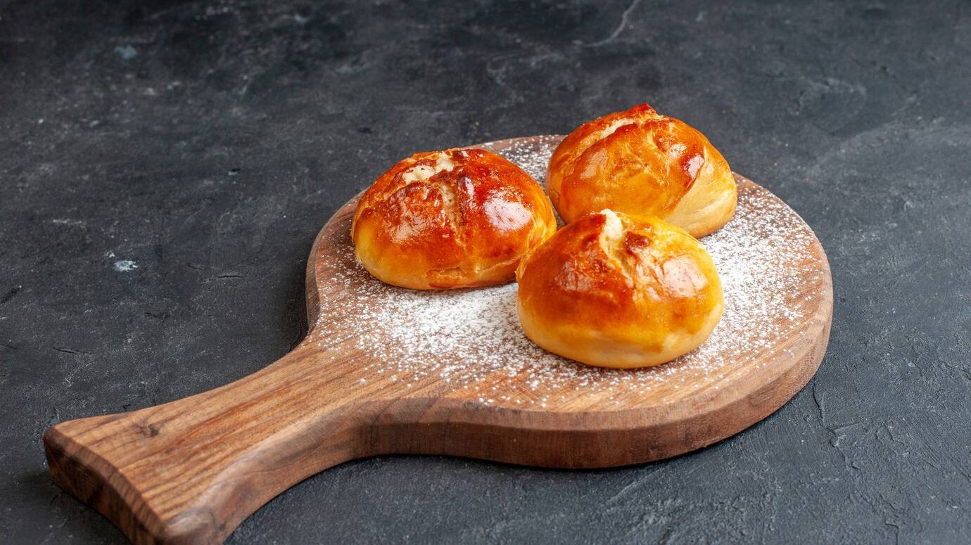 bottom-view-tasty-dinner-rolls-wood-board-black-wall_140725-144458