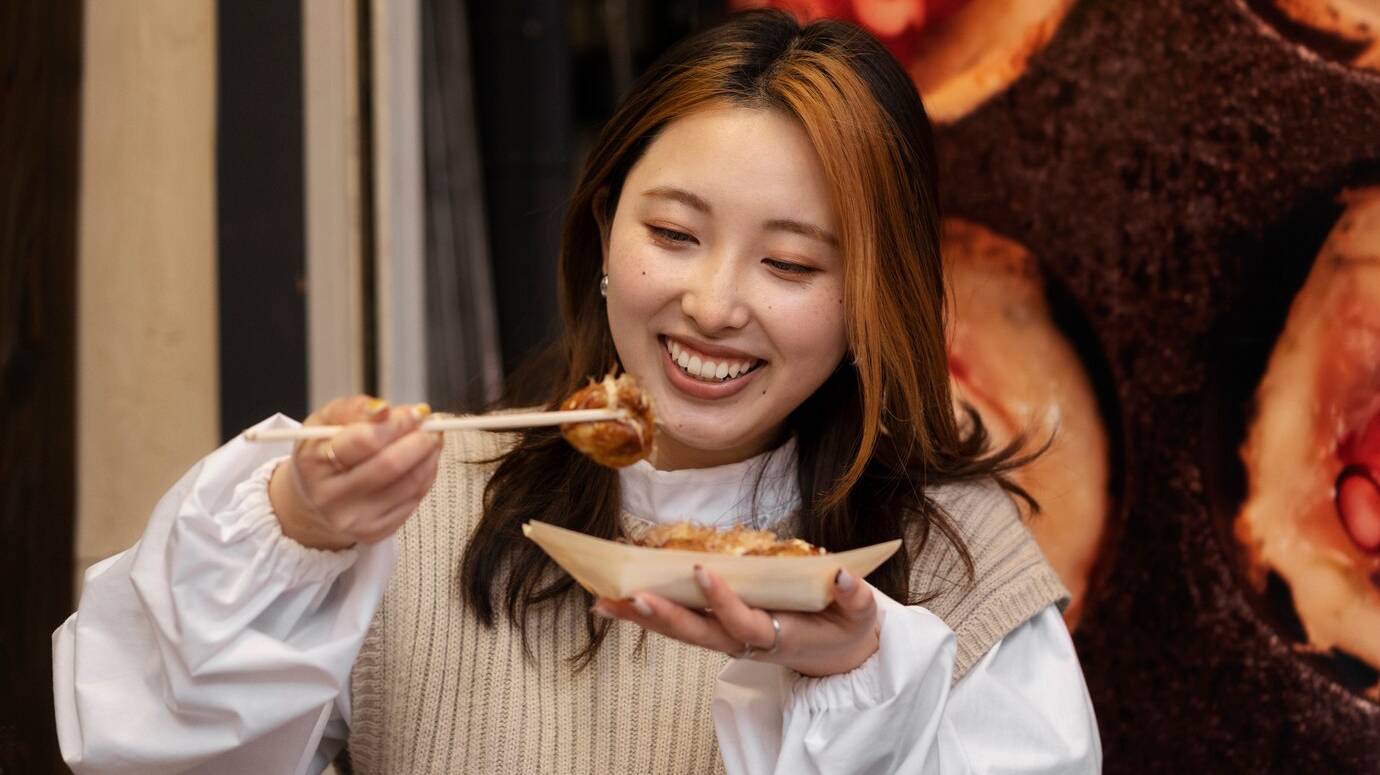 young-adult-enjoying-japanese-street-food_23-2149319429