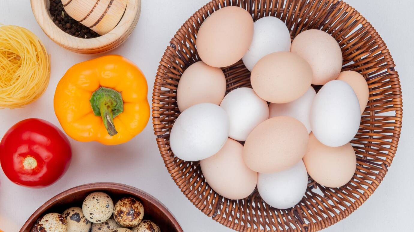 top-view-fresh-chicken-eggs-bucket-with-tomato-pepper-white-background_141793-14776