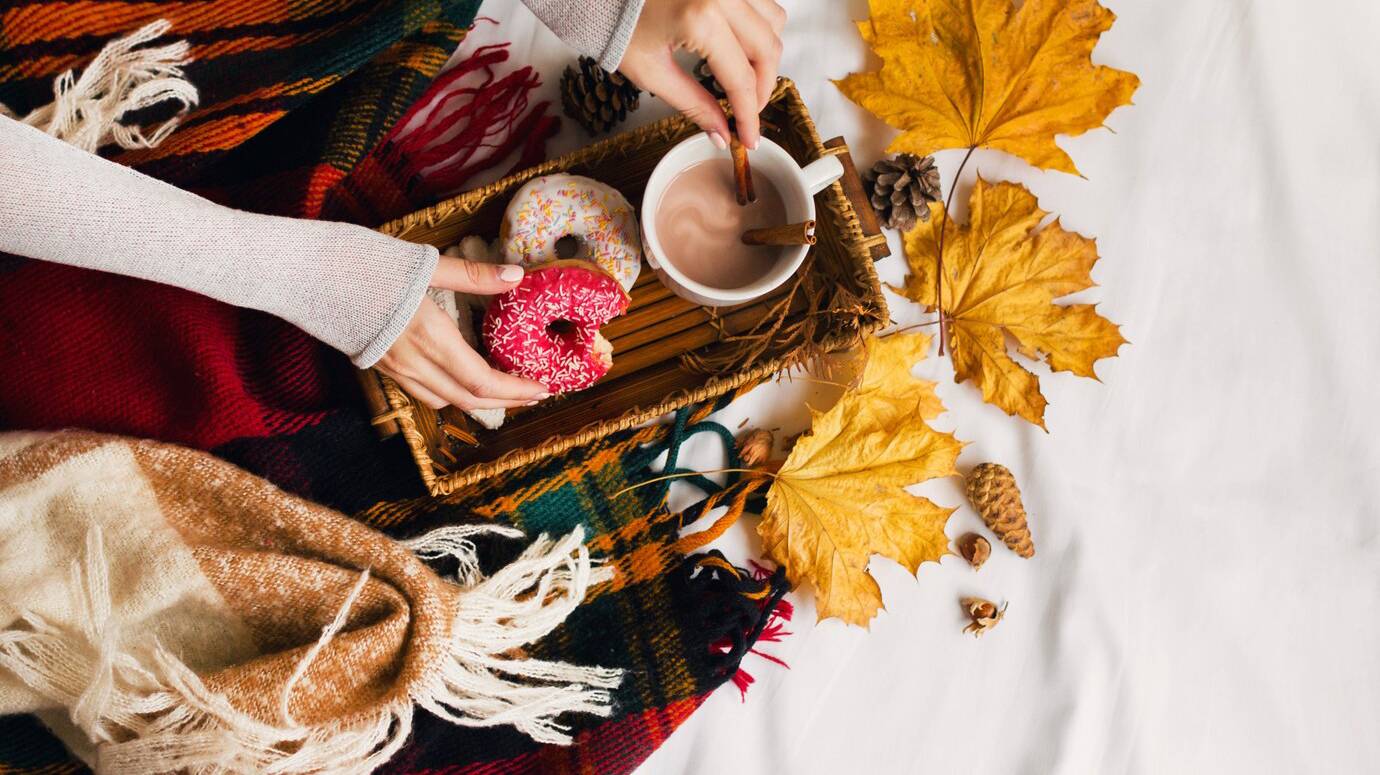 girl-eating-tasty-breakfast-bed-wooden-tray-with-cup-cacao-cinnamon-cookies-glazed-donuts_273443-2687