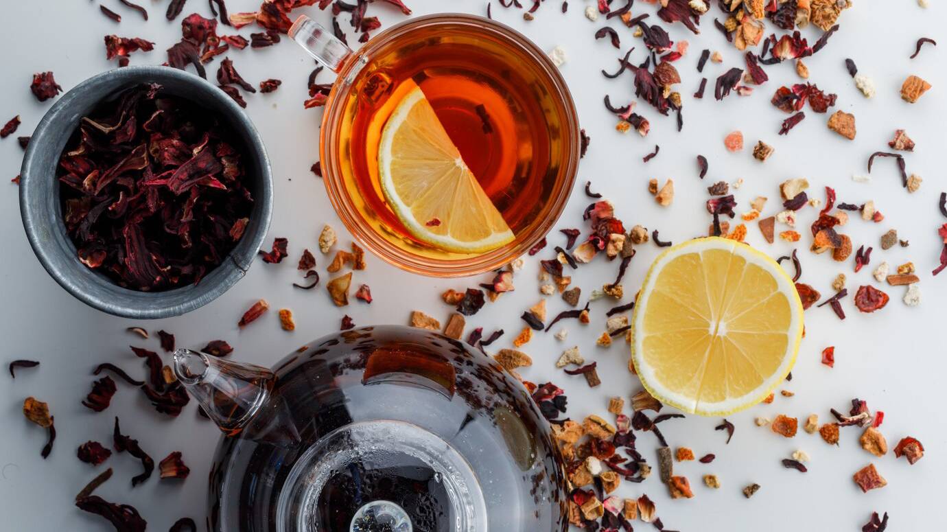 brewed-tea-with-dried-herbs-lemon-glass-teapot-white-surface_176474-6309