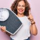 middle-age-beautiful-woman-controlling-weight-using-weighting-machine-pink-background-smiling-with-idea-question-pointing-finger-with-happy-face-number-one_839833-20676