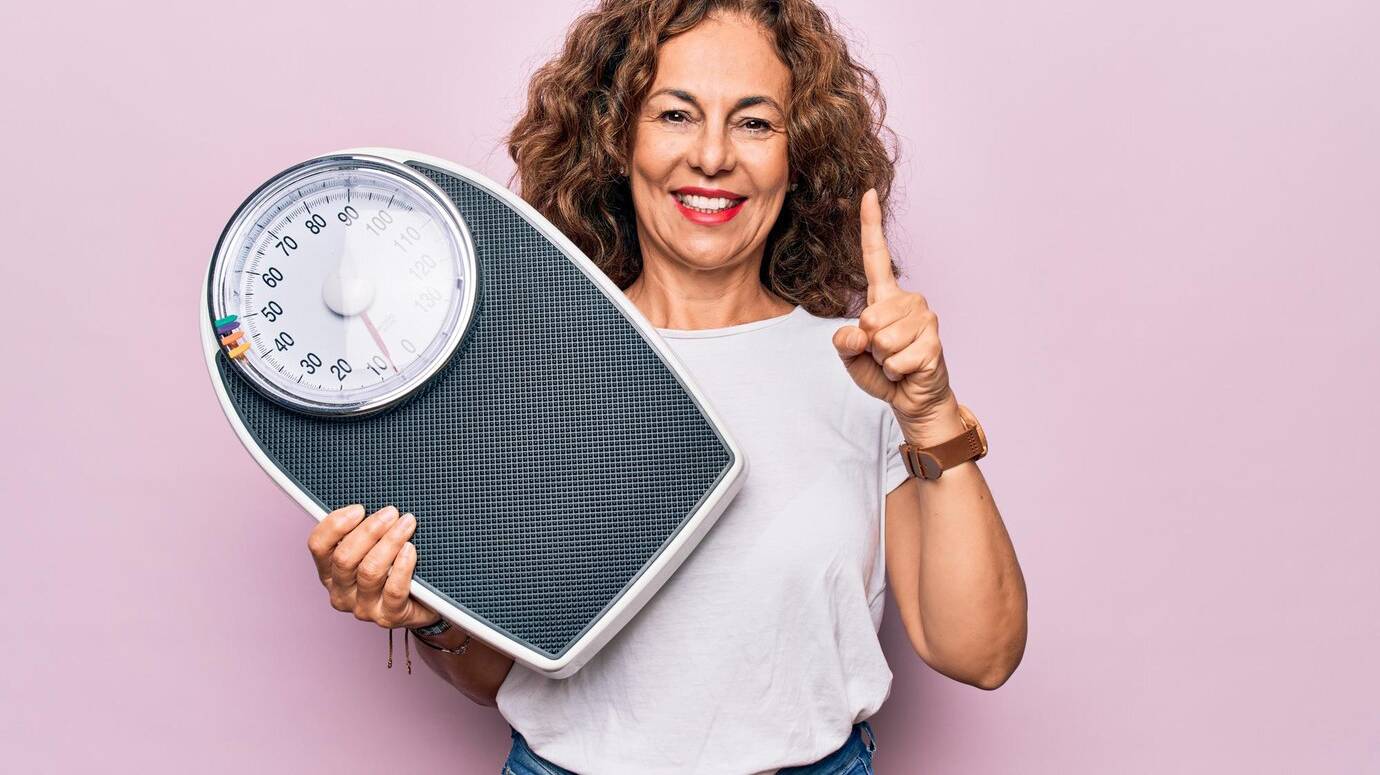 middle-age-beautiful-woman-controlling-weight-using-weighting-machine-pink-background-smiling-with-idea-question-pointing-finger-with-happy-face-number-one_839833-20676