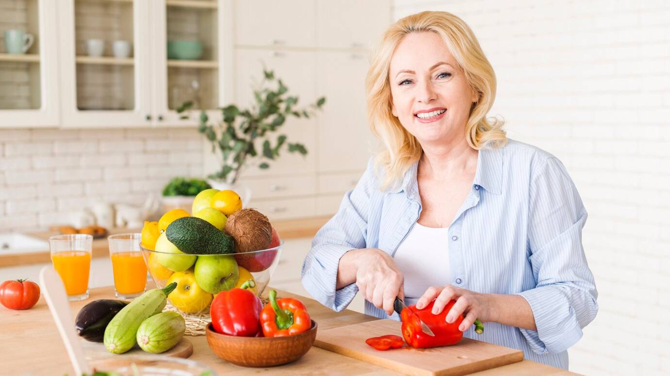 portrait-senior-woman-cutting-red-bell-pepper-with-knife-chopping-board-kitchen_23-2148128002