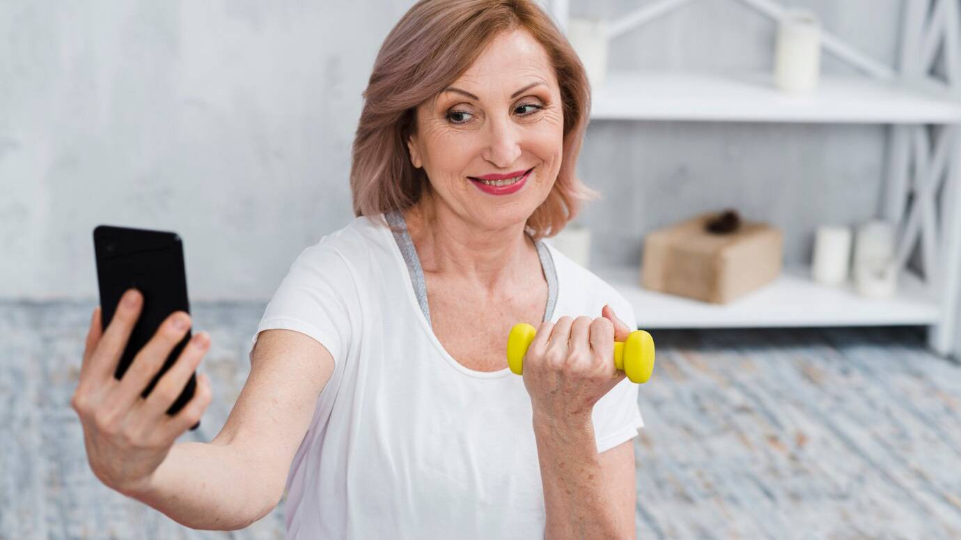 senior-woman-taking-selfie-with-dumbbells-hand_23-2148097452