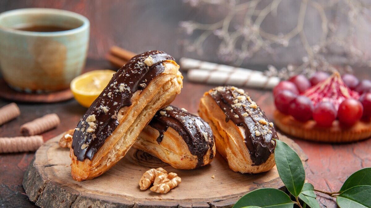 front-view-cup-tea-with-delicious-choco-eclairs-dark-background_140725-91632