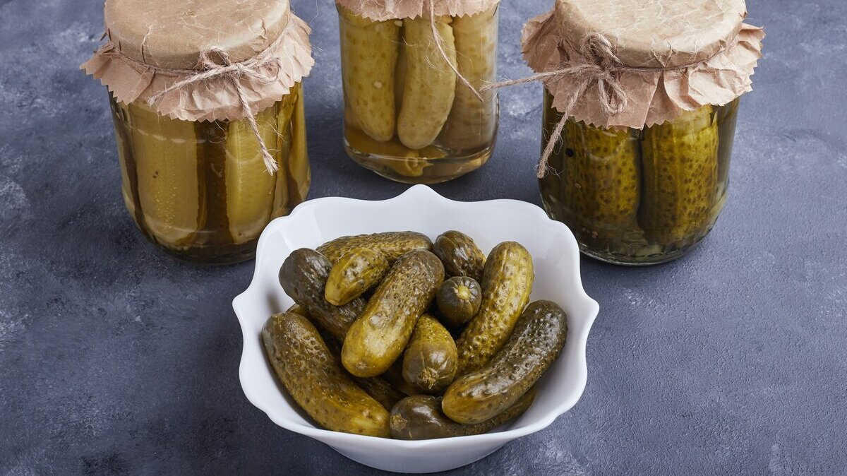 pickled-cucumbers-bowl-glass-jars-blue-surface_114579-14693